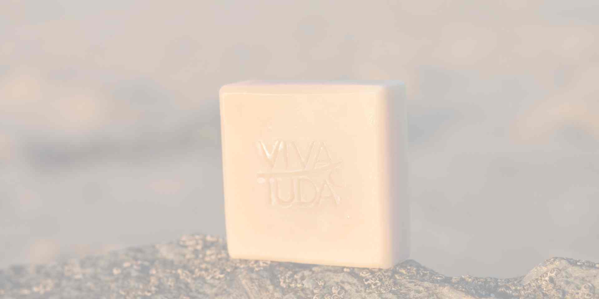 Helle, quadratische Naturseife auf einem Stein in der Sonne