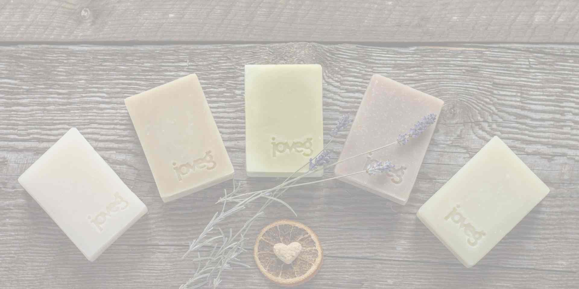 Fünf Seifen aufgefächert auf dunklem Holz, dekoriert mit Lavendel, Orangenscheibe und einem Herzchen