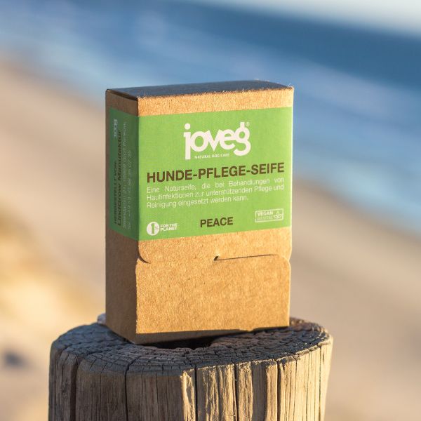 Hundeseife in braunem Karton mit grünem Etikett auf einem Pfosten mit dem Meer im Hintergrund